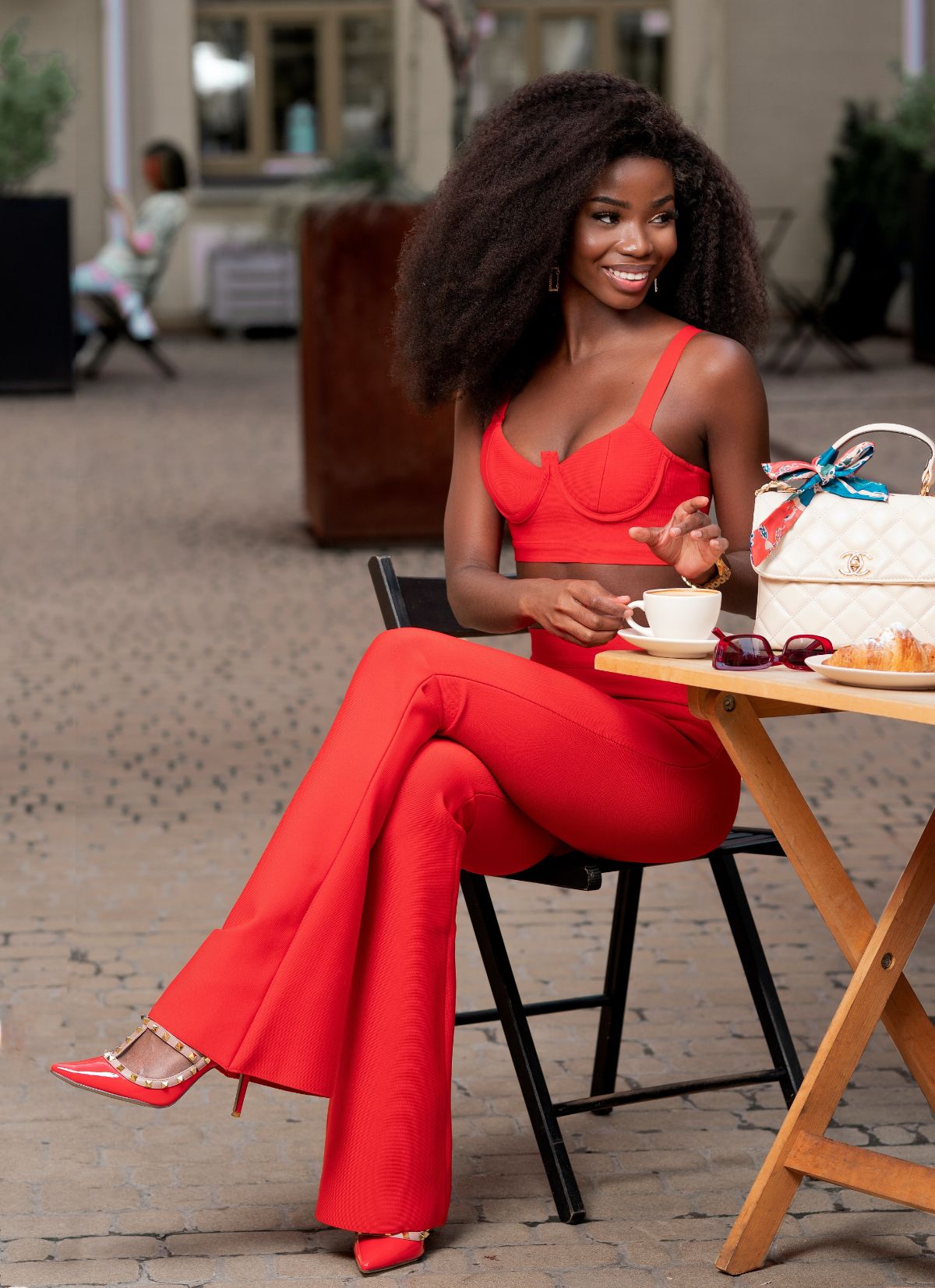 Attraktives afrikanisches Model trägt einen roten Hosenanzug und rote High Heels mit Stiletto Absätzen